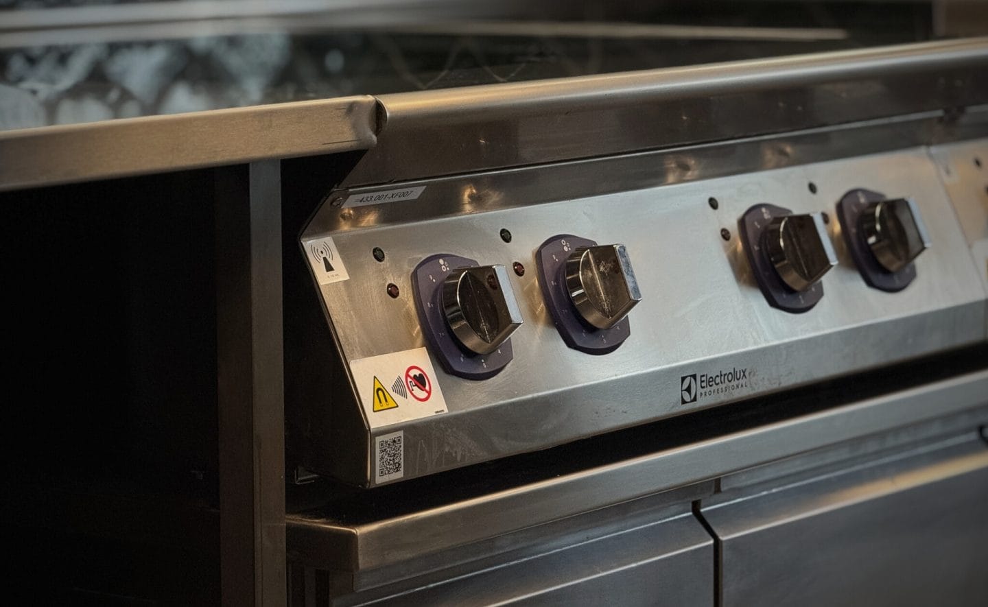 storkjøkkenutstyr koketopp med kjølebenk under stående ved siden av rustfri benk