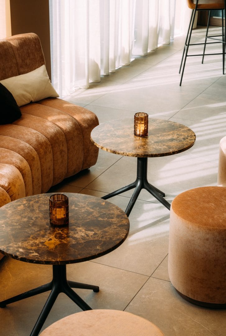 Nærbilde av bordplater og understell, med puffer og sofa på hotell innredning interiør