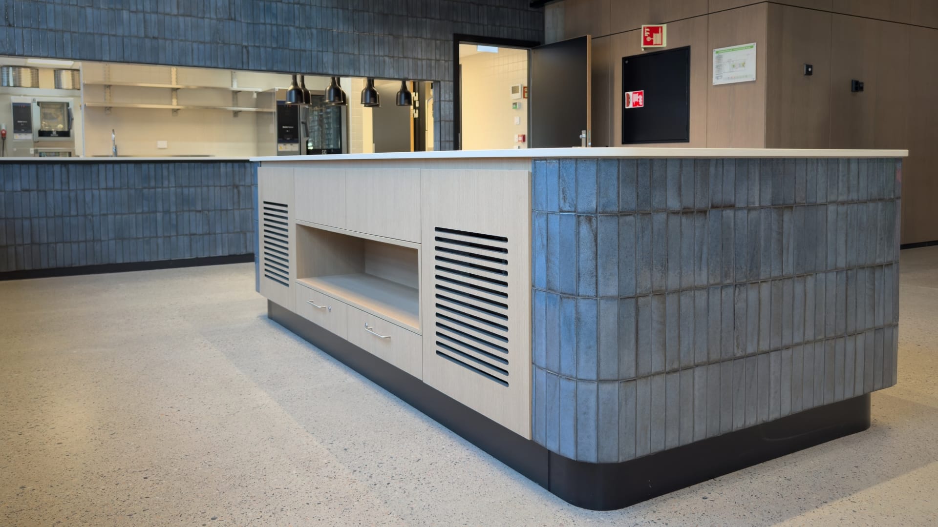 serveringsøy i kantine med eik og blå fliser ved OCCL radiumshospitalet