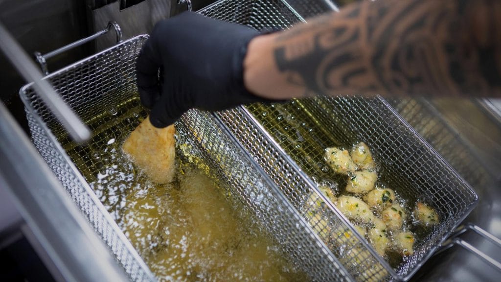 Hånd som friterer mat i olje