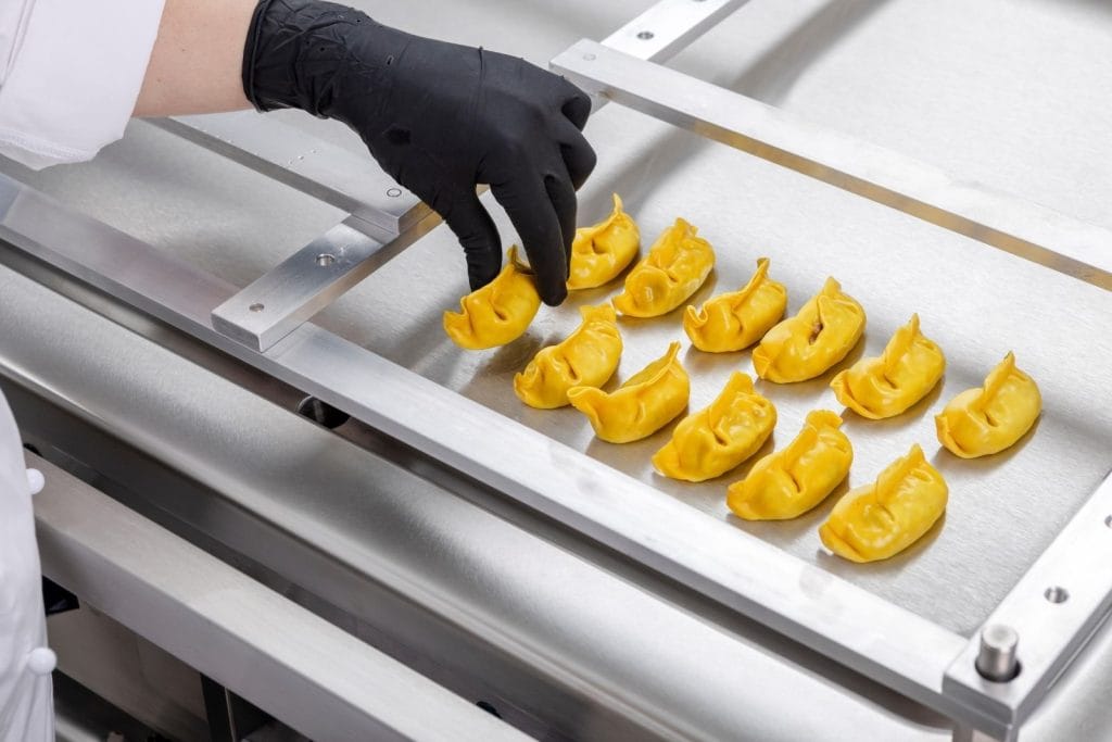 dame som steker dumplings på steketopp med slingrekant ombord i skip fartøy marine