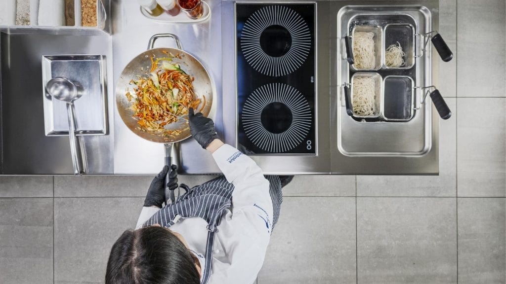 storkjøkkenutstyr kokk som koker på induksjon komfyr