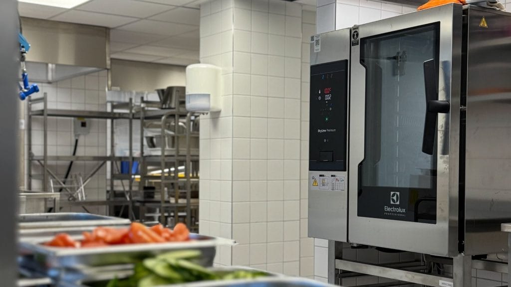 kombidamper på storkjøkken med rustfri gn brett og oppvaskrom i bakgrunn