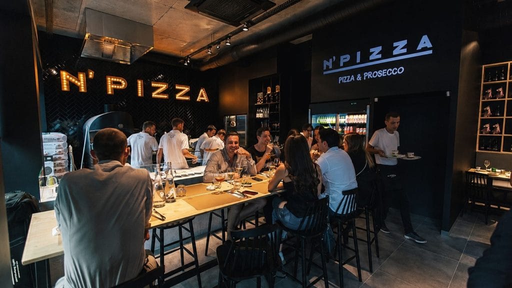 elektrisk pizzaovn ved pizzeria med gjester som sitter ved bordene og spiser