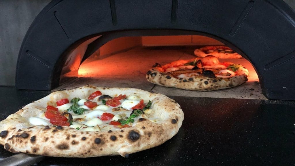 elektrisk pizzaovn med pizza som føres inn i kammerset