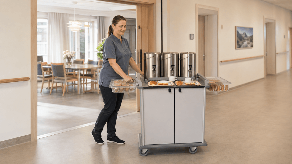 ansatt ved sykehjem som serverer kaffe og kaker fra matvogn