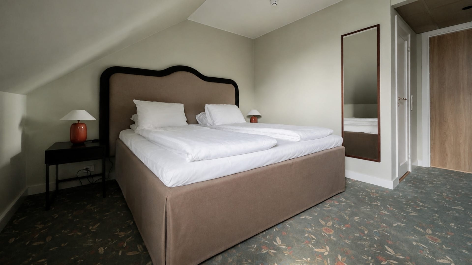 hotellrom med skråtak og teppe på gulvet