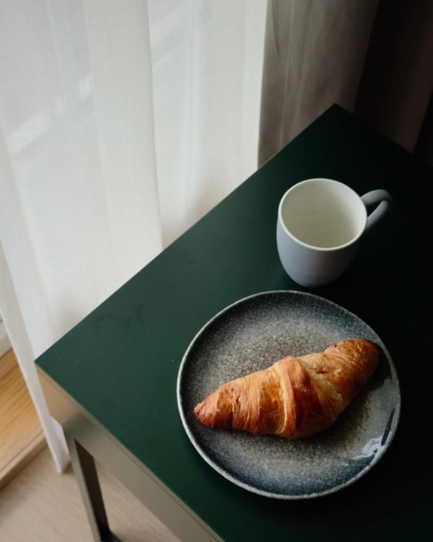 bord med croissant og kaffekopp ved vindu