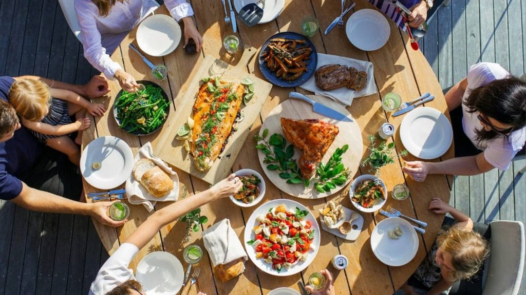 Rundt bord med masse mat og mennesker rund