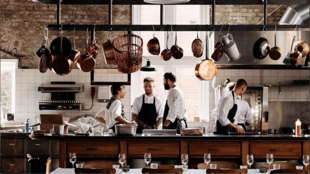 rustikk restaurant med kokker og bordbelysning i front